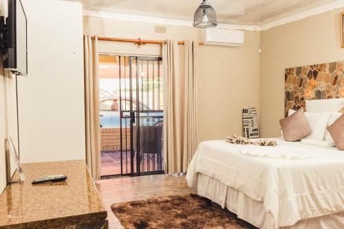 a bedroom with a bed and a sliding glass door at APICAL GUESTHOUSE in Maun