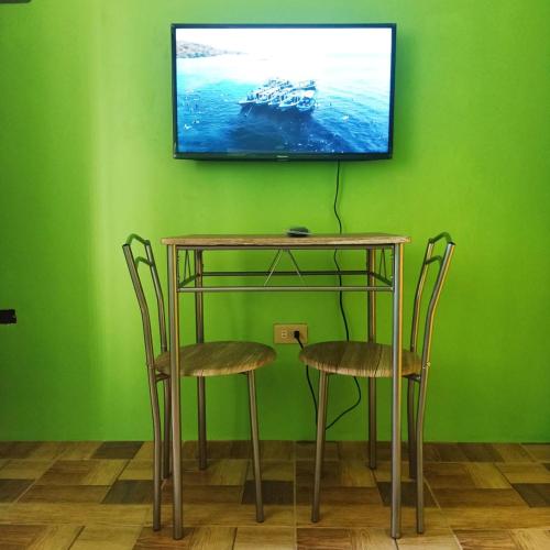 uma mesa com duas cadeiras e uma televisão numa parede verde em Blue Nest Apartment em Manila