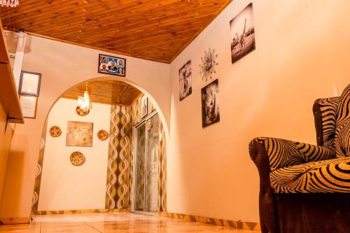 a living room with a chair and pictures on the walls at APICAL GUESTHOUSE in Maun