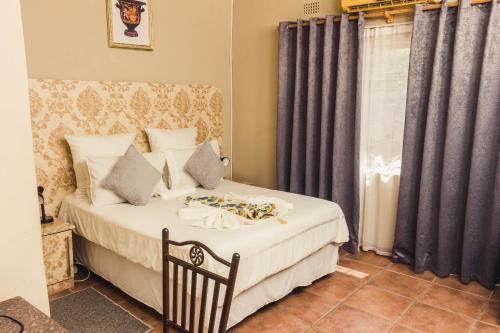 a bedroom with a bed and a window with curtains at APICAL GUESTHOUSE in Maun