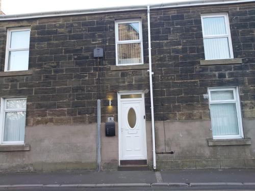 a building with a white door and a brick wall at Amble Holiday Home in Amble