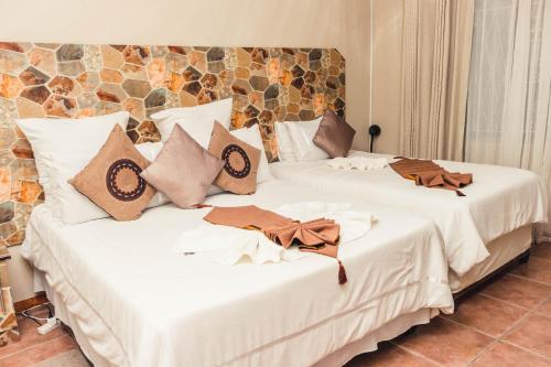two beds in a room with white sheets and pillows at APICAL GUESTHOUSE in Maun