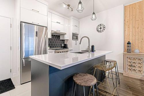 a kitchen with a sink and a counter with stools at The Hut by BnbCopilote in Quebec City