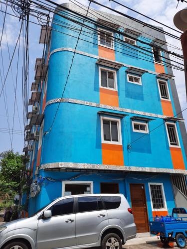 um edifício azul com uma carrinha estacionada em frente em Blue Nest Apartment em Manila