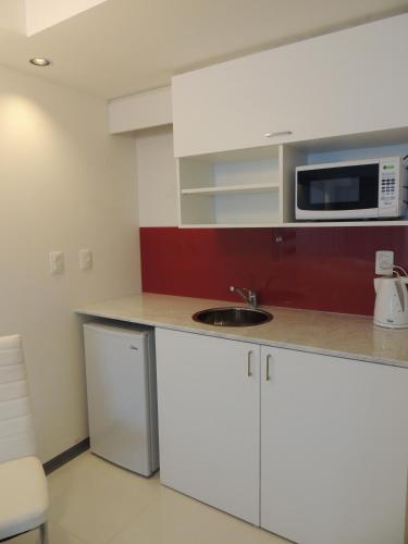 a kitchen with a sink and a microwave at Hotel Gema Luxury Suites in Montevideo