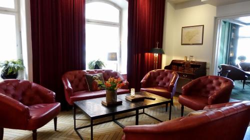 a living room with red chairs and a table at Best Western Hotel Baltic in Sundsvall