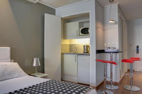 um quarto com uma cama e uma cozinha com bancos vermelhos em Golf Apartamentos em Montevidéu