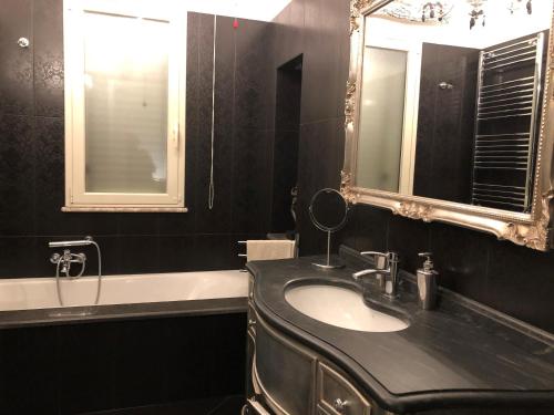 e bagno con lavandino, specchio e vasca. di Taonasi Taormina Apartments a Taormina