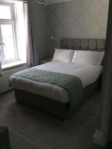a large bed in a bedroom with a window at The Epperstone in Llandudno