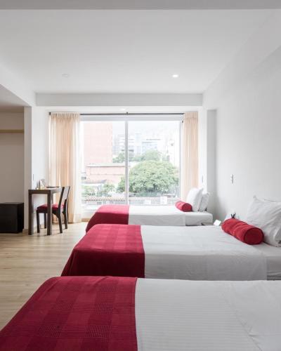 two beds in a hotel room with a window at Hotel Florencia Plaza in Medellín