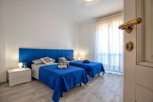 een slaapkamer met 2 bedden met blauwe lakens en een raam bij Pepita del mare in Alghero