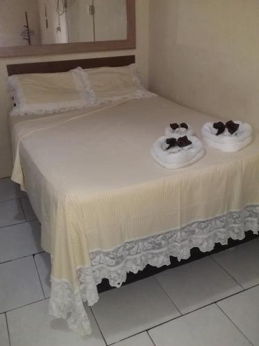 two beds with towels and hats on top of them at Pousada Lírio in Campos dos Goytacazes