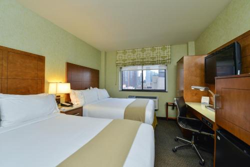 a hotel room with two beds and a desk and a tv at Holiday Inn Express Manhattan Midtown West, an IHG Hotel in New York