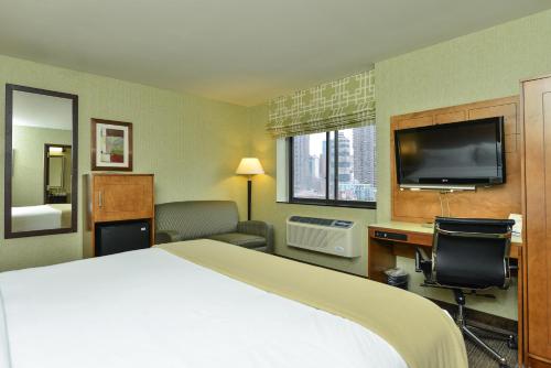 a hotel room with a bed and a flat screen tv at Holiday Inn Express Manhattan Midtown West by IHG in New York