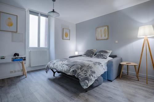 a white bedroom with a bed and a lamp at La chopine - grand studio, centre historique, hôtel de ville in Romans-sur-Isère