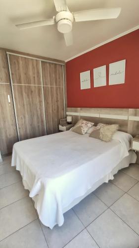 - une chambre avec un grand lit blanc et un mur rouge dans l'établissement BellaVista Departamento Temporario, à Paraná
