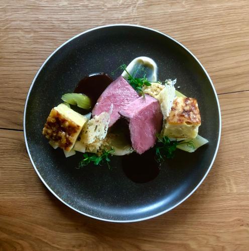 a plate of food with meat and vegetables on a table at moser-HOCHKÖNIG Genuss Wirtshaus Hotel in Maria Alm am Steinernen Meer