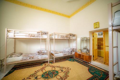 a room with three bunk beds and a rug at HOSTEL NABI BOBO in Samarkand