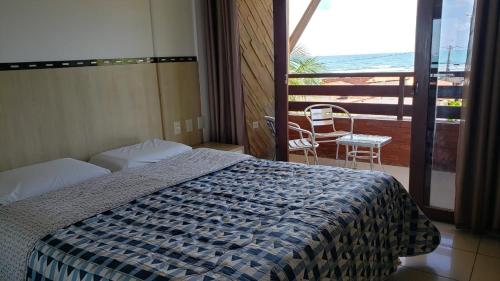 a bedroom with a bed and a balcony with a chair at Pipas Ocean Prime Vista Mar in Pipa