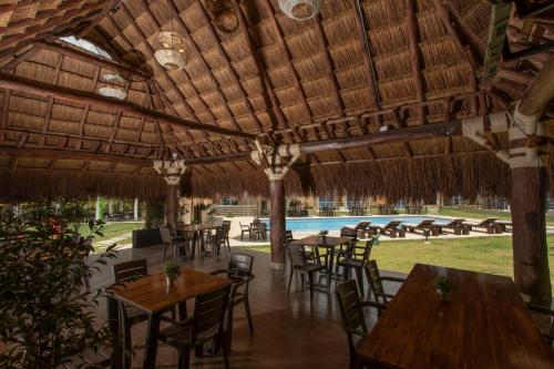 a restaurant with tables and chairs and a swimming pool at Hotel Natural Hill's by H&R in Villeta