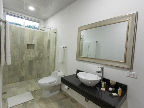 y baño con aseo, lavabo y ducha. en Hotel Natural Hill's by H&R, en Villeta
