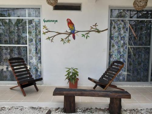 two chairs and a bench in a room with a bird on a branch at La Casa de las Aves in Bacalar