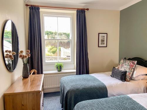 a bedroom with two beds and a window at Miners Cottage in Middleton in Teesdale