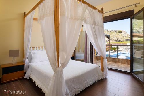 sypialnia z łóżkiem z baldachimem i balkonem w obiekcie Costa Costa Villa - Luxury villa w Kolymbii