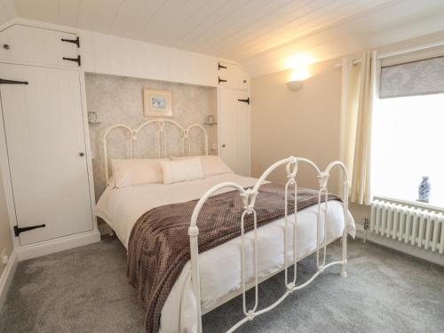 a bedroom with a white bed and a window at Rose Cottage in Deal