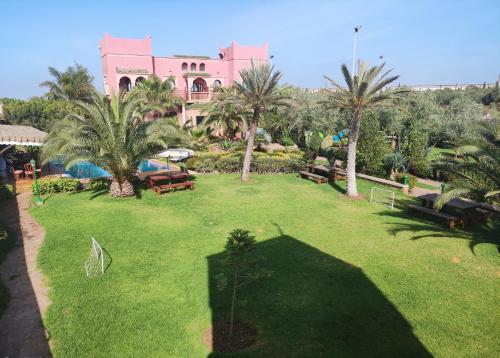 une grande cour avec des palmiers et un bâtiment rose dans l'établissement Equi Palace & SPA Near Aeroport, à Berrechid