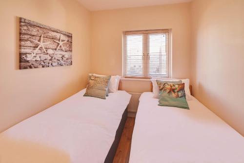 two beds in a room next to a window at Host & Stay - The Scuttlebutt Townhouse in Whitby