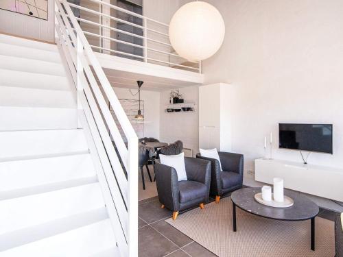 ein Wohnzimmer mit einer Treppe, einem Tisch und Stühlen in der Unterkunft 4 person holiday home in Bl vand in Blåvand