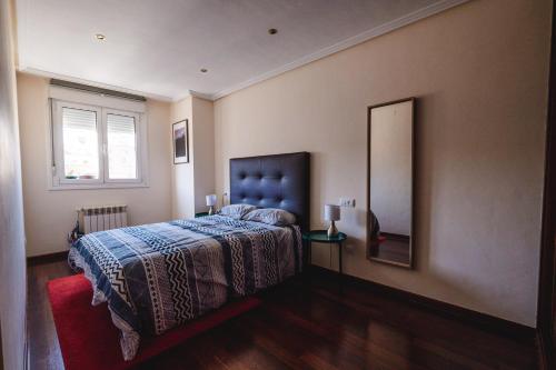 1 dormitorio con cama y espejo en la pared en El Rosal de Oviedo, en Oviedo