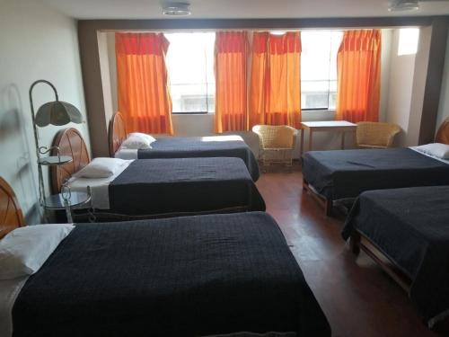 Cette chambre comprend 4 lits et des rideaux orange. dans l'établissement Hostal Espinoza II, à Arequipa