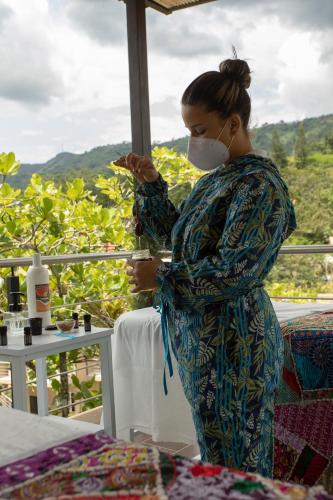 a woman wearing a mask holding a slice of pizza at Hotel Natural Hill's by H&R in Villeta