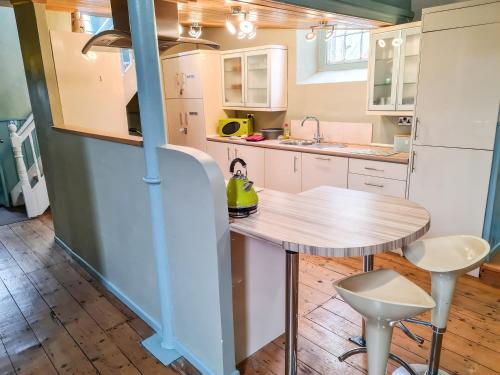 a kitchen with a table and a refrigerator at Rainforest Chapel in Longney