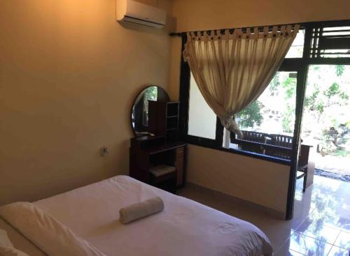 a bedroom with a bed and a large window at Gina's guest house in Sanur