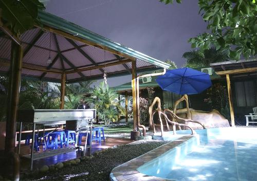 a pool with chairs and an umbrella next to a swimming pool at Cabañas Río Escondido en La Fortuna in Fortuna