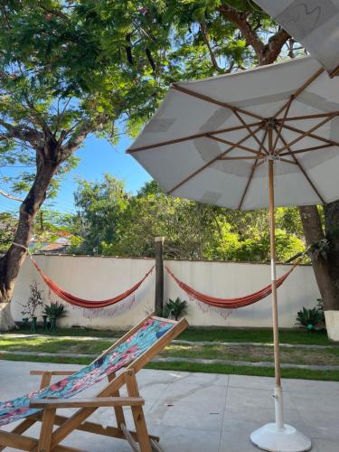 a chair and an umbrella next to a hammock at Pousada Casa Serra Alves in Búzios
