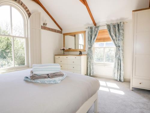 um quarto com uma cama, uma cómoda e janelas em The Old Smithy em Saint Columb Major