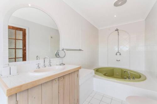 ein weißes Badezimmer mit einer Badewanne und einem Waschbecken in der Unterkunft Casa Del Rio - LJHooker Yamba in Ashby