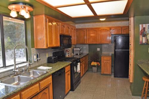 a kitchen with wooden cabinets and a black refrigerator at The Kern Lodge in Kernville
