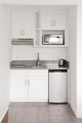 a white kitchen with a sink and a microwave at Hollywood Hills Hotel in Los Angeles
