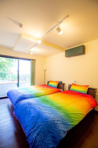 a rainbow colored bed in a room with a window at 天弓イン in Kachabaru
