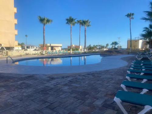 a large swimming pool with chairs and palm trees at Palacio de cristal, Fiesta de cortes 101, Casa Hermar in Puerto Peñasco