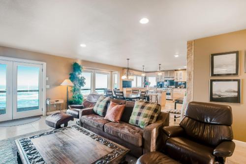 a living room with a couch and chairs and a kitchen at Surf and Sand in Lincoln City