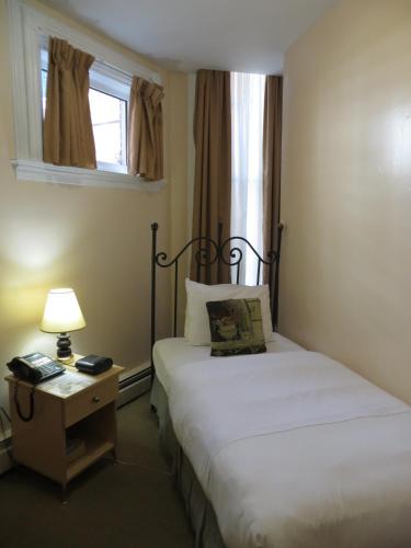 a bedroom with two beds and a lamp and a window at Victoria's Mansion Guest House in Toronto