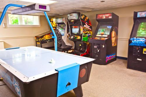 a room with two arcade games and a white table at Holly Tree Resort in West Yarmouth
