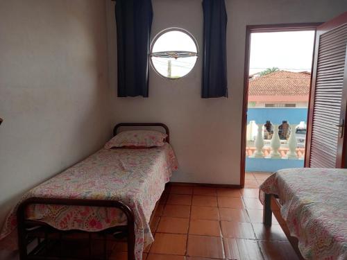 a bedroom with two twin beds and a window at Casa Azul no Centro Ilha Comprida in Ilha Comprida