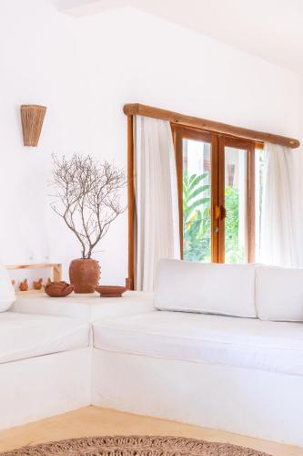 a white room with a white couch and a window at CasaLô Hotel in Jericoacoara